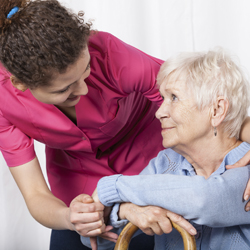 Woman standing with arm around senior woman with cane sitting