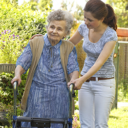 Community service worker helping older woman with walking frame