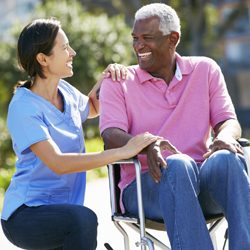Woman kneeling down and talking to a man in a wheelchair