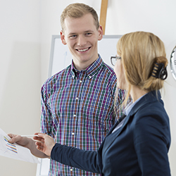 Two people standing and discussing a document