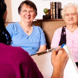 Woman visiting elderly clients in their home and taking notes