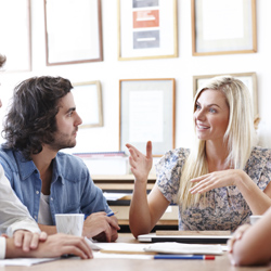 Three people seated at a table and discussing something