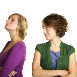 Two women with arms crossed, one who is looking away