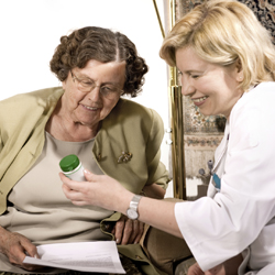 Health care worker showing bottle of medication to an older woman