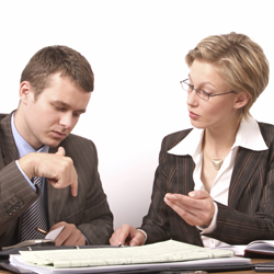 Two workers seated at a table and discussing information