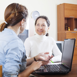 Worker at desk with computer talking to her supervisor