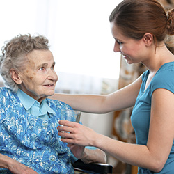 Home carer attending to an elderly woman