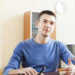 Man seated at office desk talking to someone