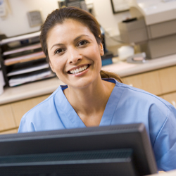 Profile of smiling nurse sitting at a computer