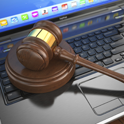 A gavel resting on the keyboard of a laptop computer
