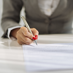 Close up of a woman’s hand writing with a pen on paper