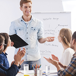 Young man holding a clipboard and conducting a presentation to small group