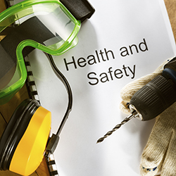 Health and safety manual with goggles, gloves, drill and earmuffs