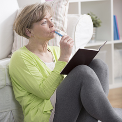 Woman sitting down and writing in her diary